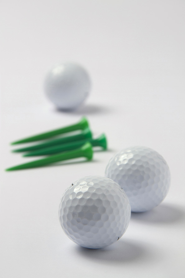 golf balls and golf tees lying on white surface