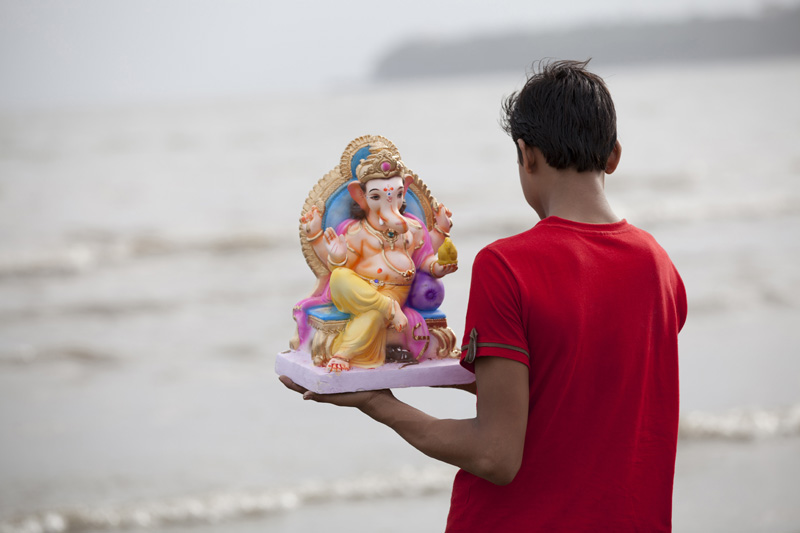 boy ready to immerse lord ganesha idol into river 