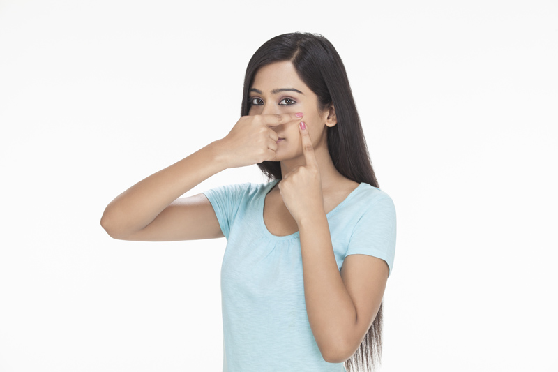 a girl squeezing a pimple on her cheek