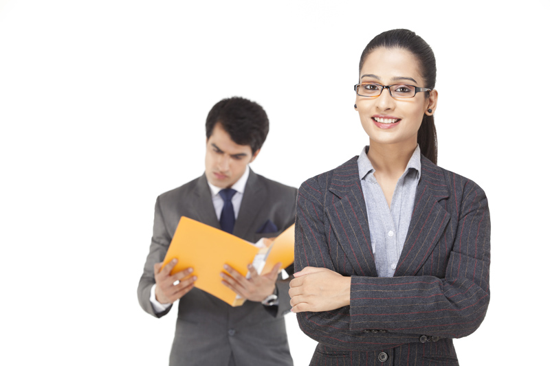 business girl smiling and posing while male executive in the backgroun