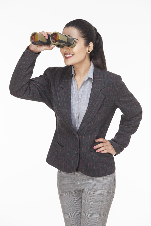 businesswoman smiling and looking through binocular