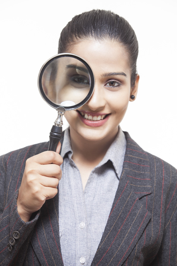 girl smiling while holding magnifying glass