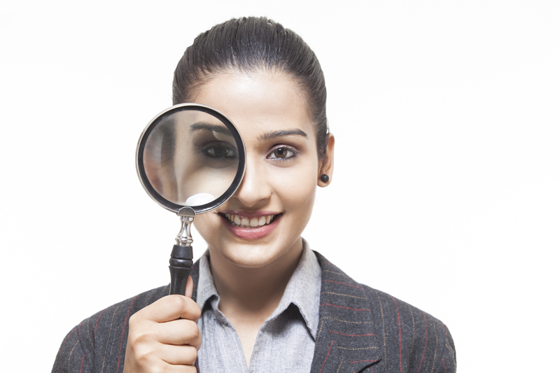 beautiful businesswoman looking at something with magnifying glass