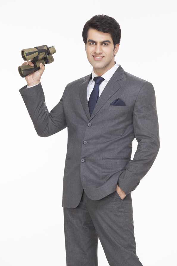 young businessman holding binoculars while posing  