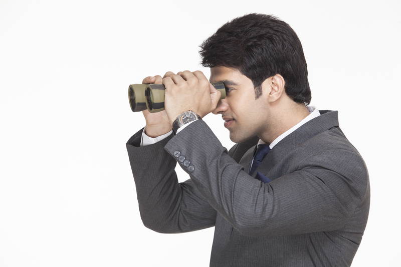 side view of a businessman looking at something from binoculars 