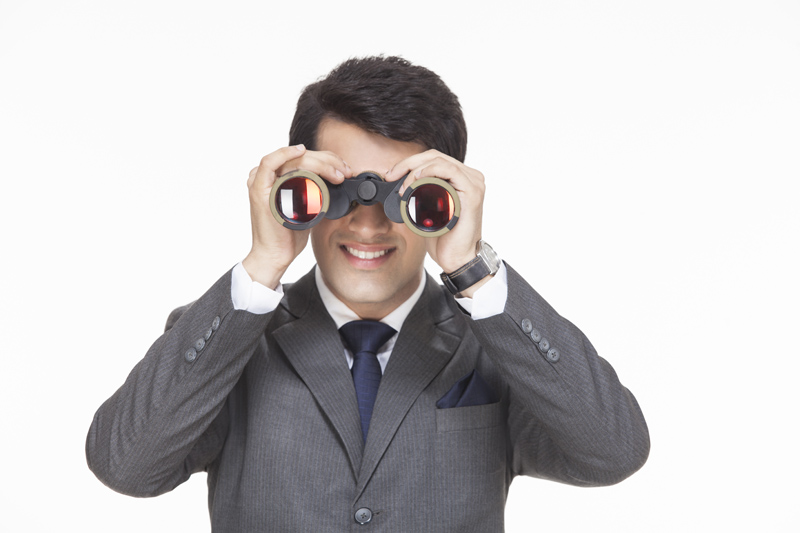businessman smiling while looking through binoculars 