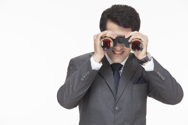 young businessman looking for something through binoculars 