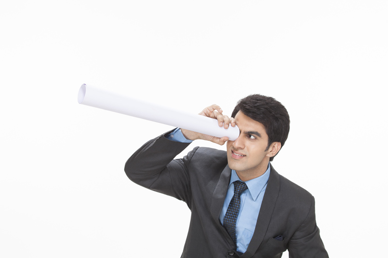 businessman looking from rolled chart