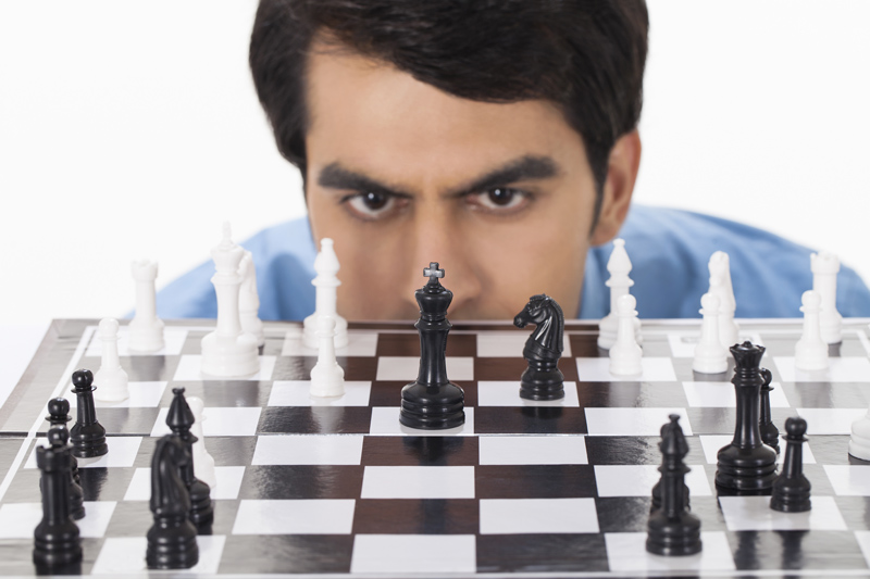 man deeply thinking while looking at chess pawns 