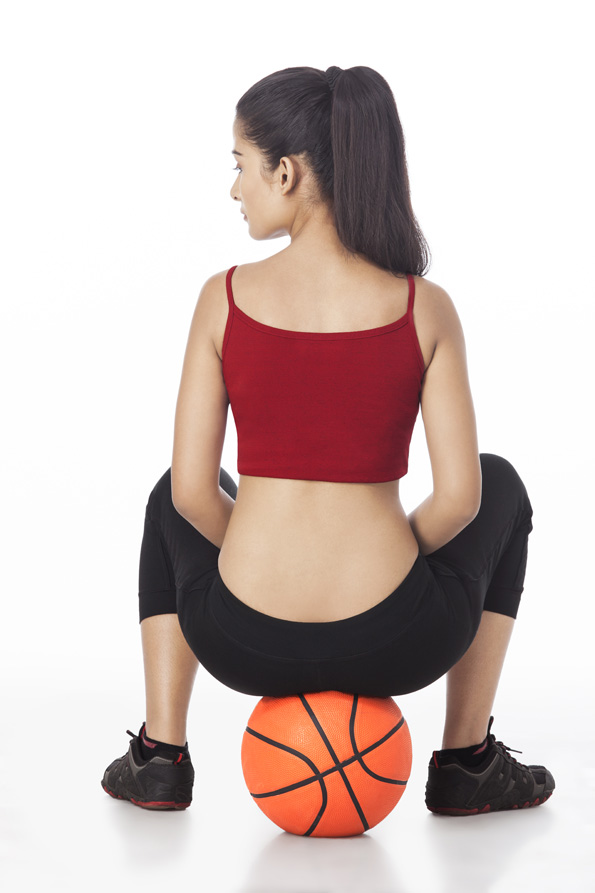 girl showing her back while sitting on basketball