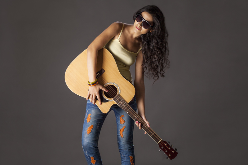 Girl wearing sunglasses and playing guitar