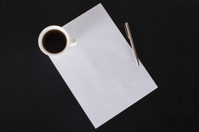 coffee mug and pen lying on paper