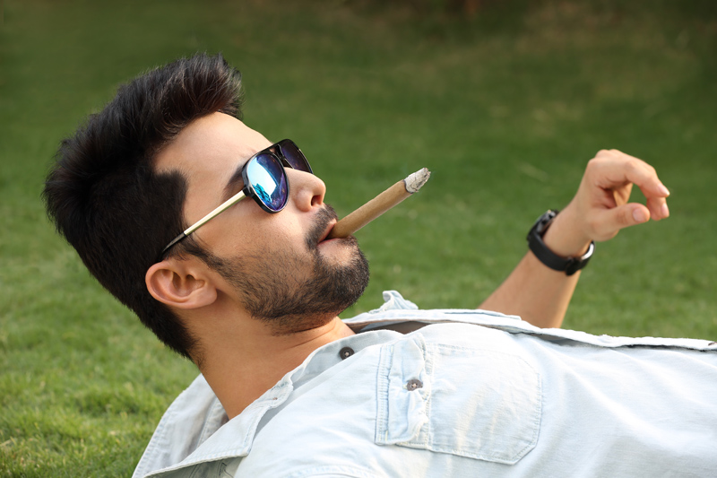 man lying down and smoking cigar