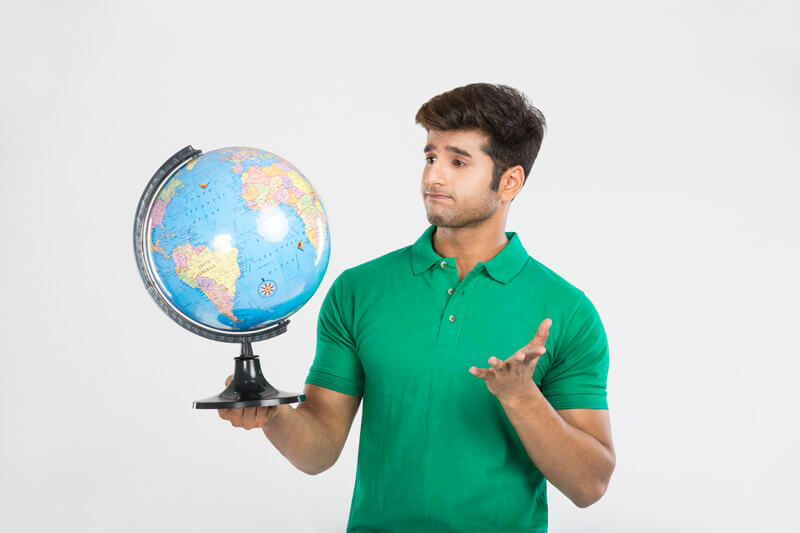 man gesturing while looking at the world globe map