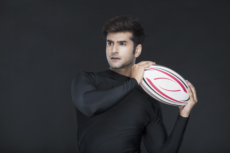 man holding rugby ball while posing for the camera 