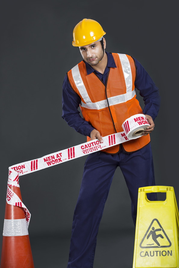 worker applying caution tape 