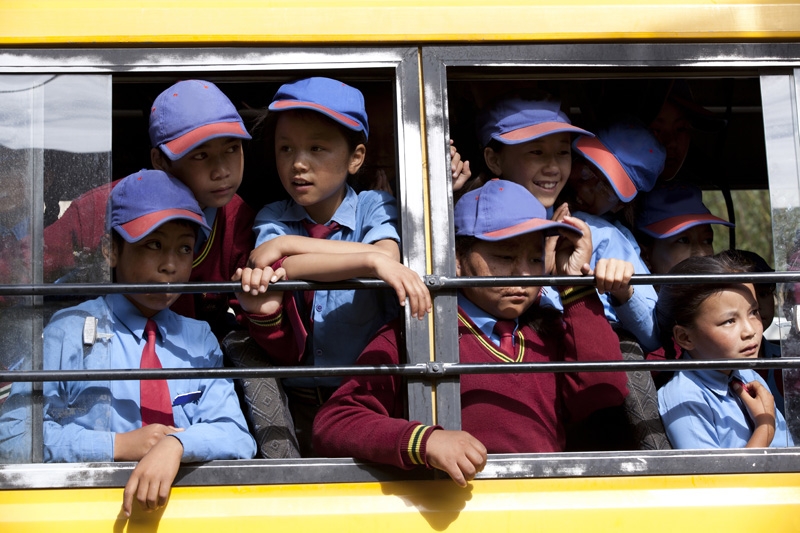 children peeking from window of their school bus