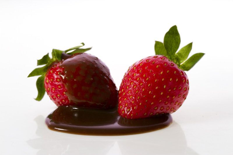 two fresh strawberries dipped with chocolate syrup