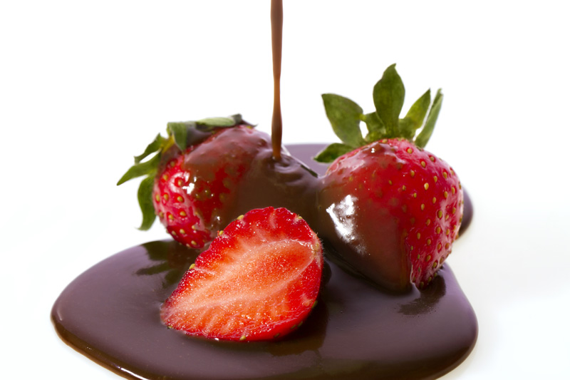 chocolate syrup poured on strawberries from above 