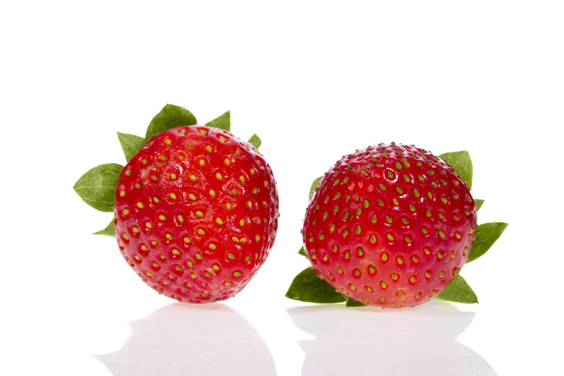 pair of strawberries lying against white background 