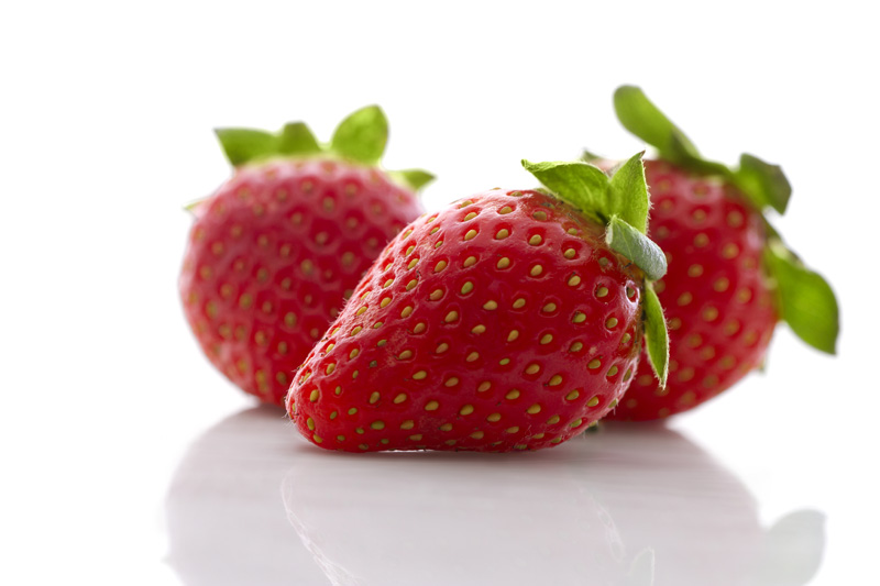 close up shot of three fresh strawberries against white background 