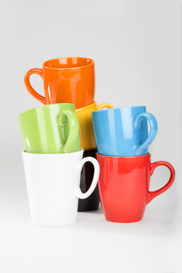 set of colourful cups lying against white background 