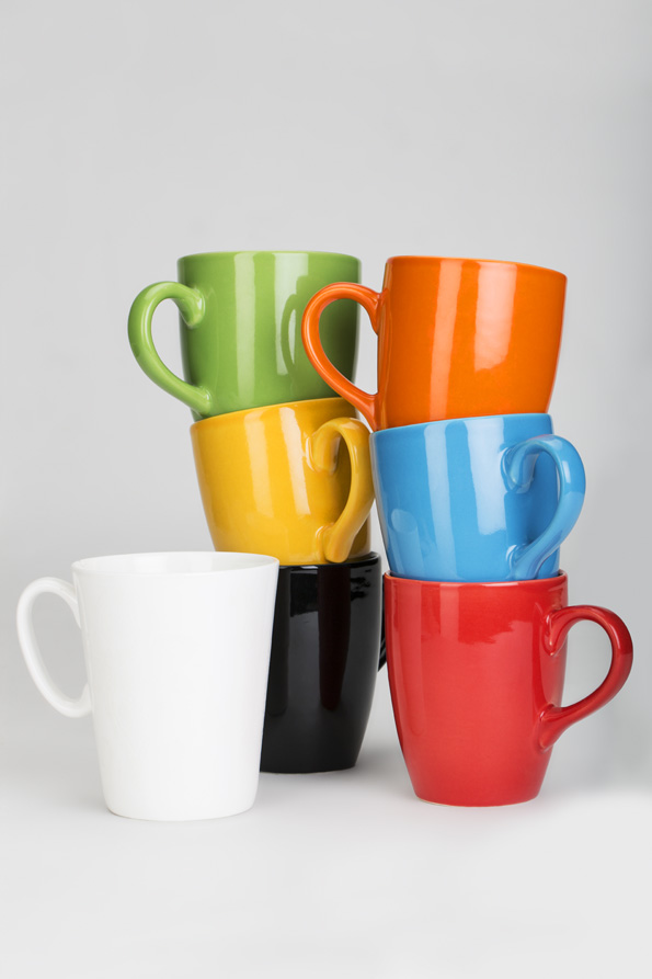 stack colourful cups lying against white background 