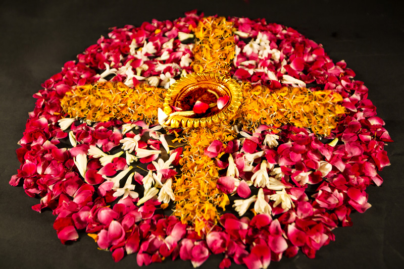 rangoli made by flower petals alongwith diya