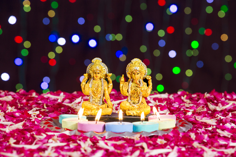 lord ganesha and luxmi statues with diyas in front