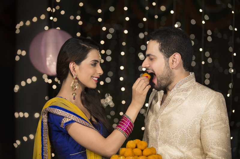 couple celebrating diwali with ladoos 