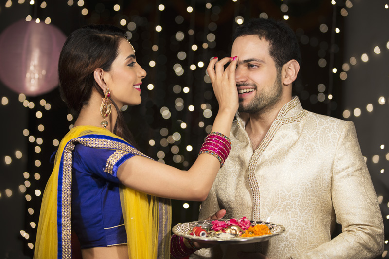 couple celebrating diwali and wife applying tika to husband 