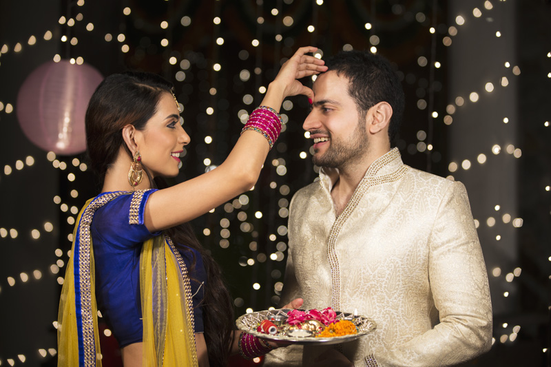 couple celebrating diwali and wife applying tika to husband 