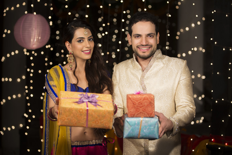 couple holding diwali gifts and smiling