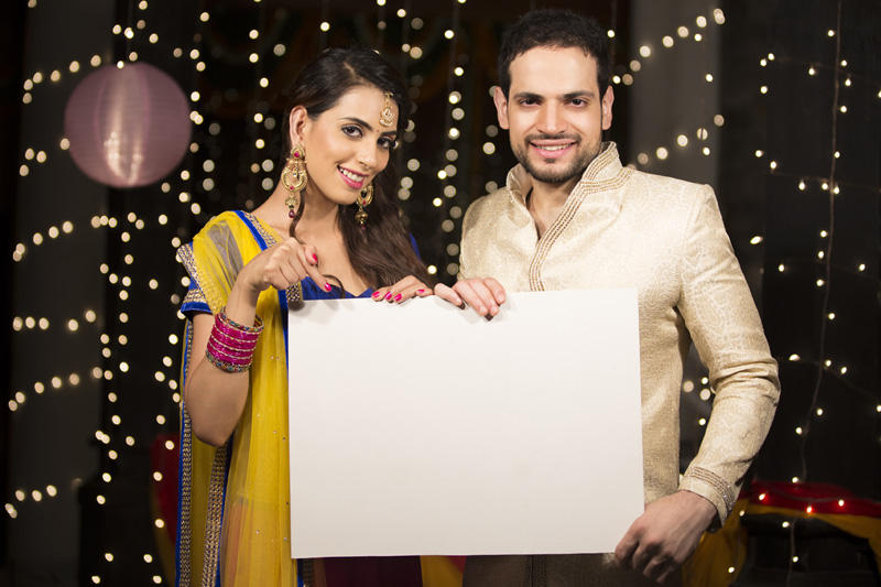 couple posing with a white message board on diwali