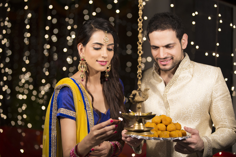 couple celebrating diwali by lighting lamp