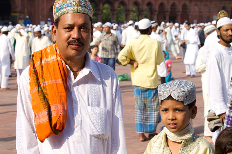muslim man with son posing with people in the background