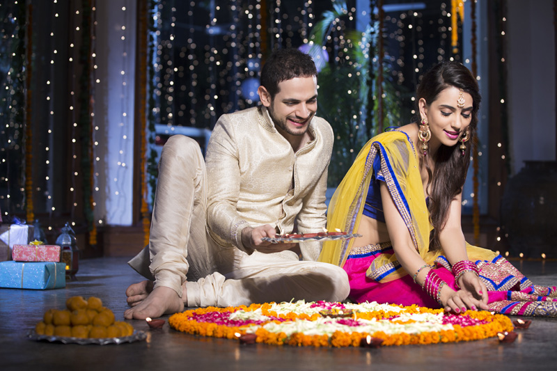 couple sitting and making rangoli on diwali
