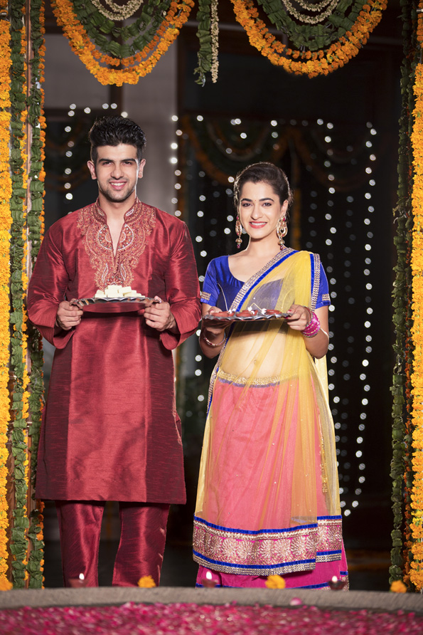 couple standing with sweets and thali in hand