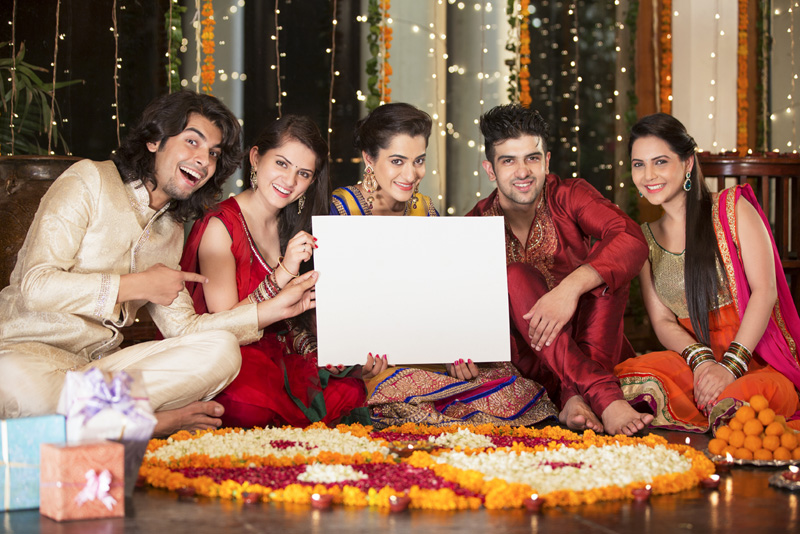 couples in traditional wear sitting with a message board 