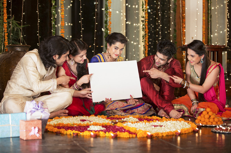 couples in traditional wear sitting with a message board 