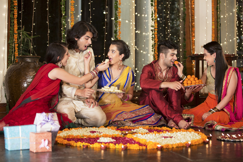couples celebrating diwali by feeding each other ladoos 