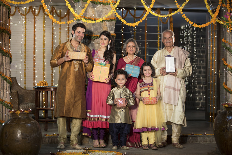 family in traditional wear standing with diwali gifts 