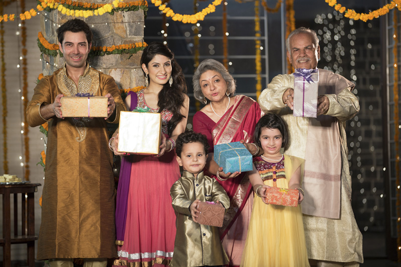 family in traditional wear standing with diwali gifts 
