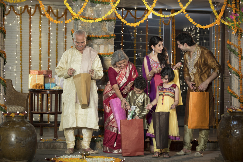  family in traditional wear standing with diwali gifts 