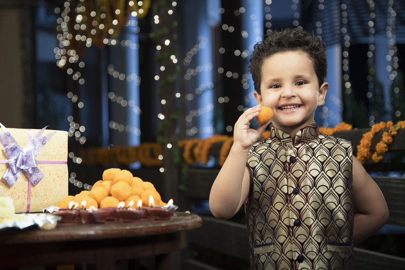 cheerful young boy eating sweets on diwali