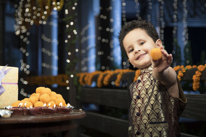 cheerful young boy eating sweets on diwali