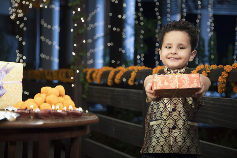 cheerful young boy offering a present on diwali