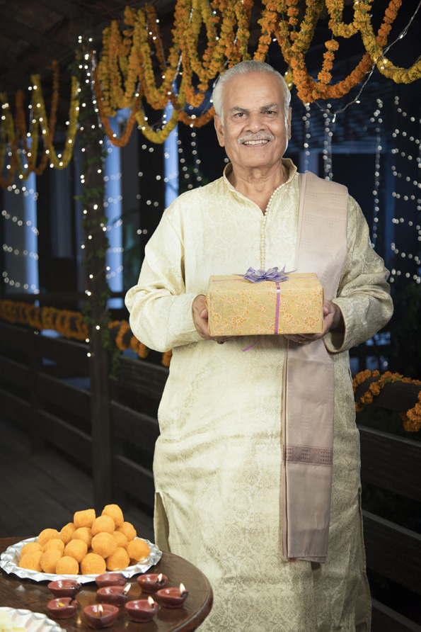 cheerful old man offering a present on diwali