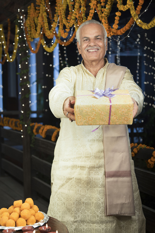 cheerful old man offering a present on diwali