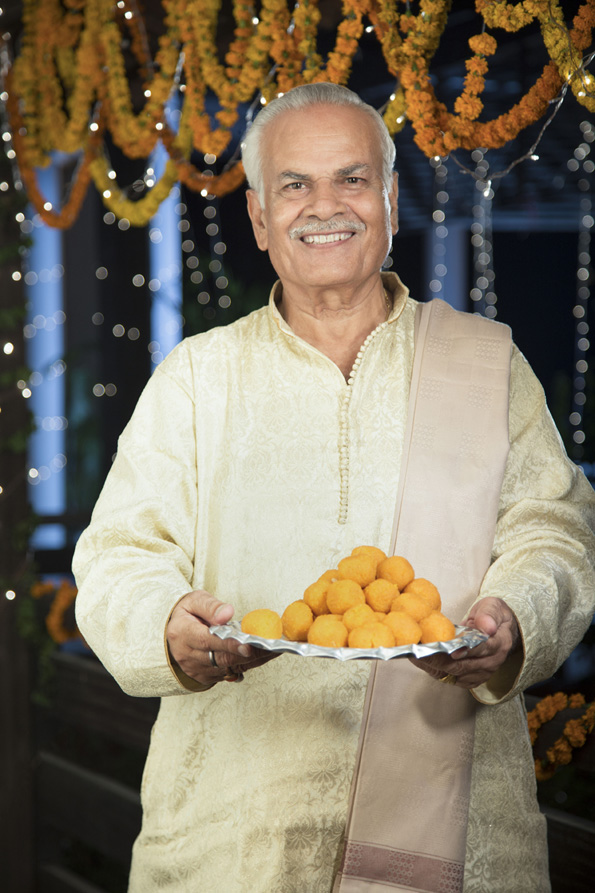 cheerful old man offering sweets on diwali